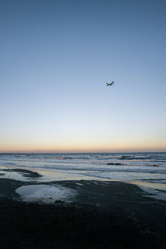 airplane flying over the beach in larnaca at sunset