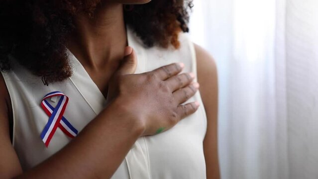 black woman proud to be Dominican puts her hand on her chest when listening to the national anthem