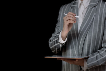 business woman holding a tablet and a stylus in her hands on a black background, space for text on the left