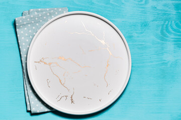 Minimalism style composition with marble plate and napkin on blue wooden background top view. Copy space for your design.