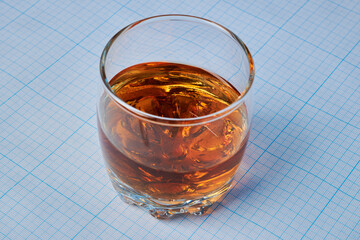Whisky glass - photo on a graph paper. Whisky glass is laying on millimeter grid page. Brown drink,...