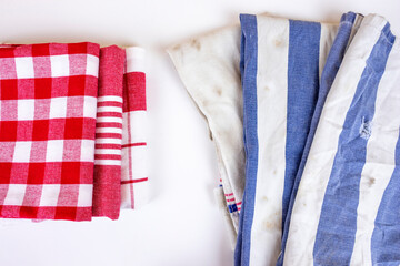 Three new red checkered kitchen picnic towels folded versus old dirty torn blue cloth towels....