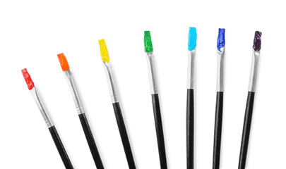 Brushes with colorful paints on white background, top view
