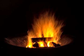 Fototapeta premium beautiful campfire in a fire bowl with smooth flames and firewood - long exposure