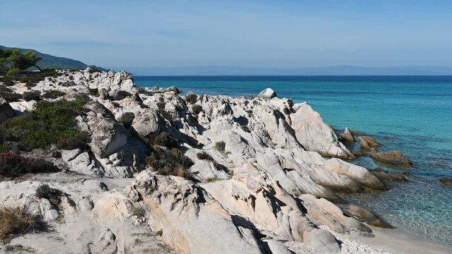 Aegean sea coast of Greece. Rocky shore, sparce vegetation, blue transparent water