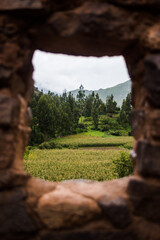 An ancient building in Peru opening up to a mountain landscape. 