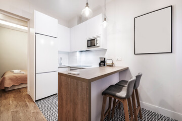 open plan kitchen with white cabinets and table with high stools in vacation rental apartment