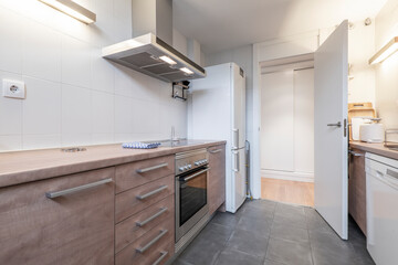 Fototapeta na wymiar Kitchen with wooden furniture and worktop in the same tone with white and stainless steel appliances with gray terrazzo floors