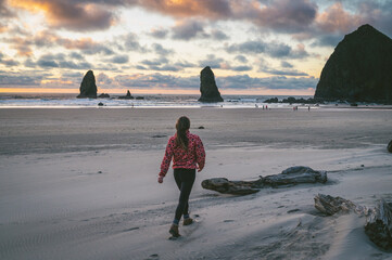 Female walking on Cannon Beach at sunset