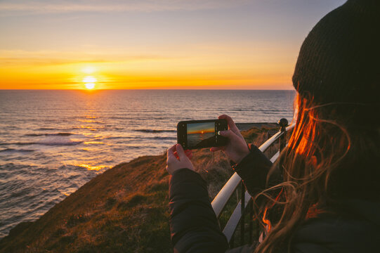 Female taking a photo of sunset on the Washington Coast
