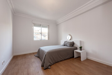 Fototapeta na wymiar Bedroom with gray bed and bedspread with aluminum window and white furniture on wooden floor