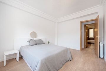 Bedroom with gray bed and bedspread with white furniture, aluminum radiator and oak carpentry