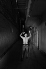 A Disturbed Inmate walks along a dark Asylum Corridor - obrazy, fototapety, plakaty