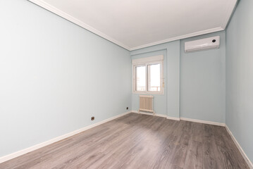 empty bedroom with green walls and parquet floor with air conditioner and white aluminum window