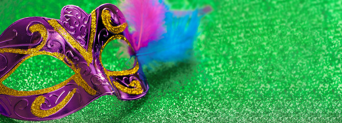 Purple carnival mask on green shiny background. Mardi Gras or Fat Tuesday symbol.