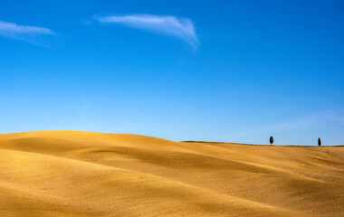 Fototapeta na wymiar Beautiful landscape of a plowed field and a blue sky in Tuscany, Italy