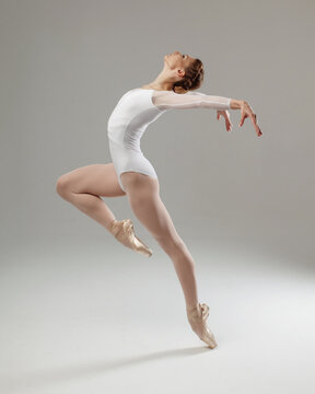 woman ballet dancer doing passe isolated on gray background