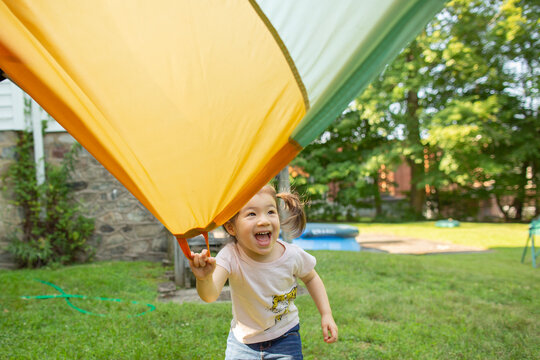 Happy Young Girl Holds Parachute Handle in Backyard
