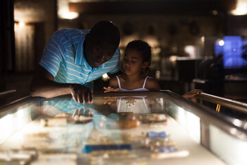 African American father and daughter looking at stands with exhibits at historical museum