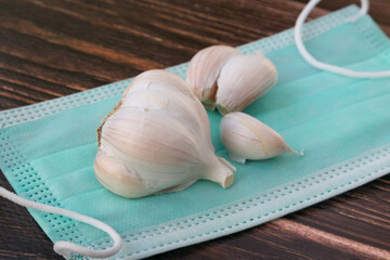 Garlic cloves and Bulb is on the medical mask Natural antibiotic made from garlic.Concept of alternative medicine and recovery from coronavirus - 487892578