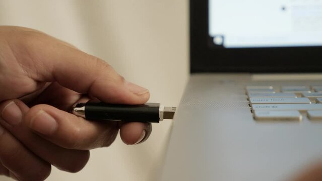 Person inserting plug in flashdisk into usb port in laptop personal computer, data transfer device concept