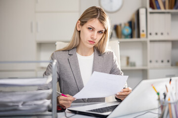 Portrait of unhappy business woman working on laptop, she has problems at work in modern office