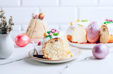 Slice of Easter kulich cake on a plate over white marble table