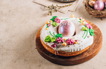 Traditionl Easter kulich cake on wooden board over rustic stone background.