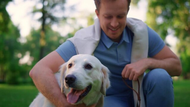 Smiling man holding leash in park. Owner cuddle close eyes cuddling lovely dog