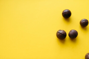 Composition with whole macadamia nuts on yellow background. Flat lay