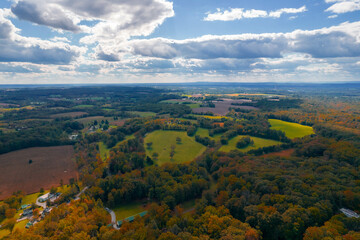 Fototapeta na wymiar Aerial Drone View of Fall Forest With Foliage Amongst Blue Cloudy Skies