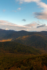 View of Mountains with Autumn Foliage Trees with a Cloudy Blue Sky