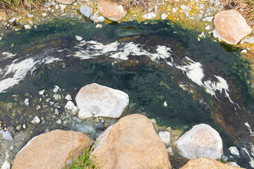 Close up shot of clear and clean water flow stream in natural hot spring during summer time shows beautiful water surface and colorful rock. It is destination for tourist visiting on vacation.