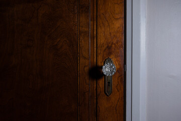 Wooden door with an antique, crystal doorknob in a haunted house