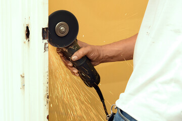 Man adjusting a lock on a door, using an electric polisher