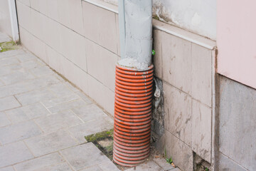 Drainage of a building right under the ground. Plastic and steel tube. Duct. Build. Front. Clean. Detail. Tile. Sidewalk. Street