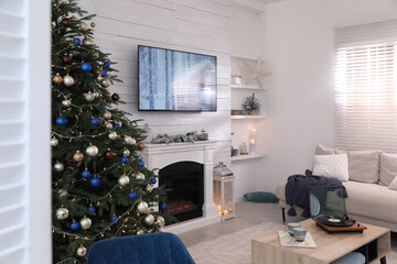 Stylish living room interior with modern TV, fireplace and Christmas tree