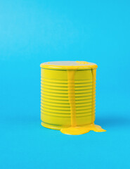 An overflowing jar with leaking yellow paint on a blue background. Trending colors.