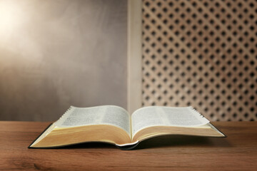 Beam of light over open Bible on wooden table