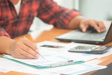 A businessman analyzing investment charts at workplace and using laptop and touch tablet.
