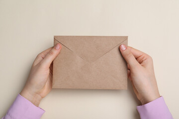 Woman with brown envelope on beige background top view