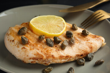 Delicious chicken fillet with capers and lemon on plate, closeup
