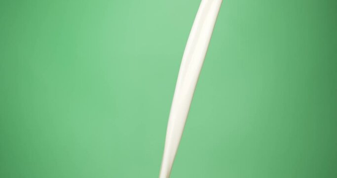 Cow milk is pouring and flowing slowly. Pure and pasteurized milk on green background. Food concept.