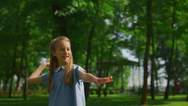 Smiling girl throw ball on green meadow closeup. Happy kid play catch in park.
