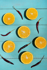 Orange halves with chili pepper on turquoise background