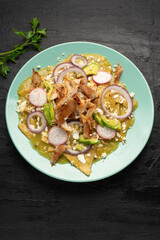 Green chilaquiles with pork meat and cheese. Mexican food