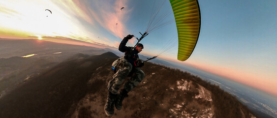 Man flying the paragliding at sunset