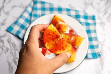 Orange halves with chili pepper powder and chamoy on white background