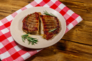 Grilled pork steaks with rosemary on wooden table