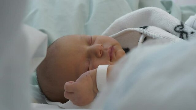 newborn baby sleeping moves hand with hospital bracelet